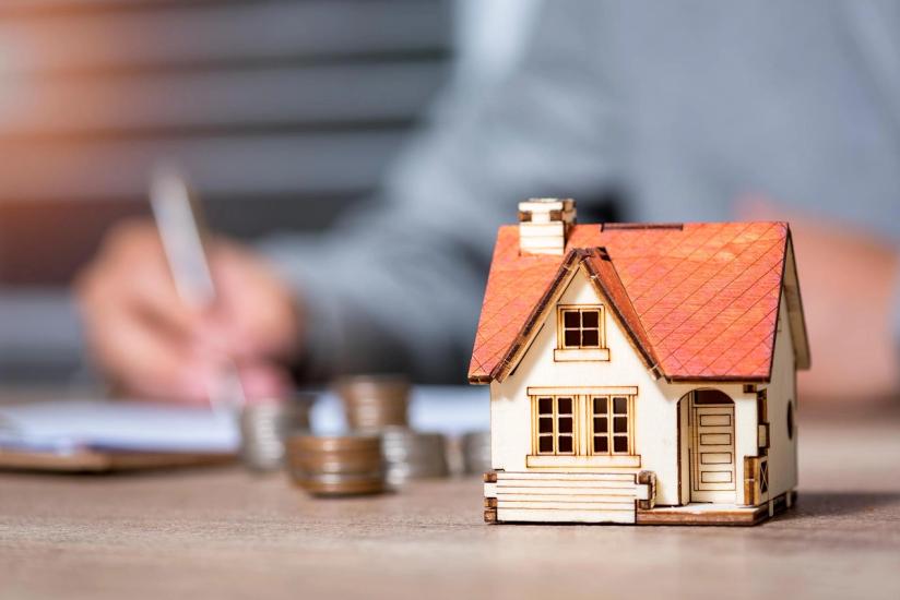 house in forefront, person signing contract in background