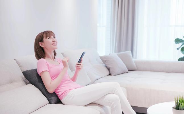 Woman sitting on couch uses smartphone to control smart home devices