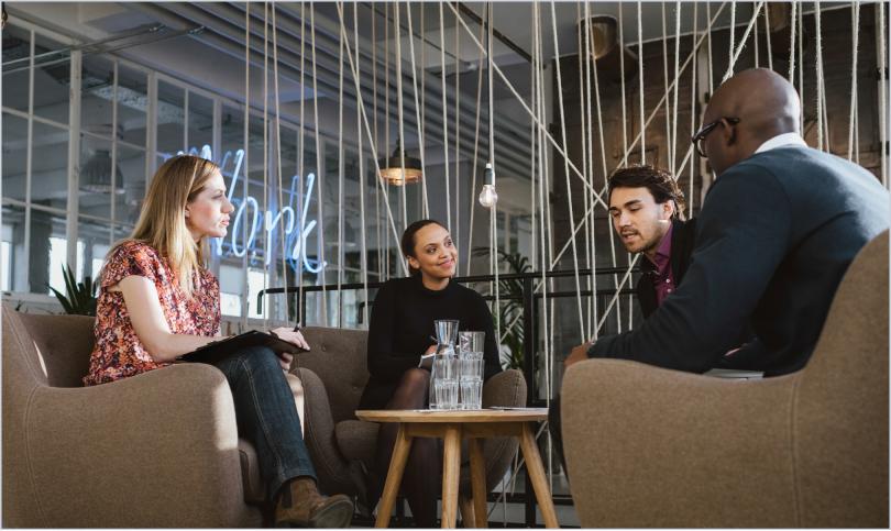 four people talking around a coffee table