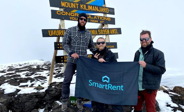 SmartRent trekkers holding up SmartRent flag at peak of Kilimanjaro