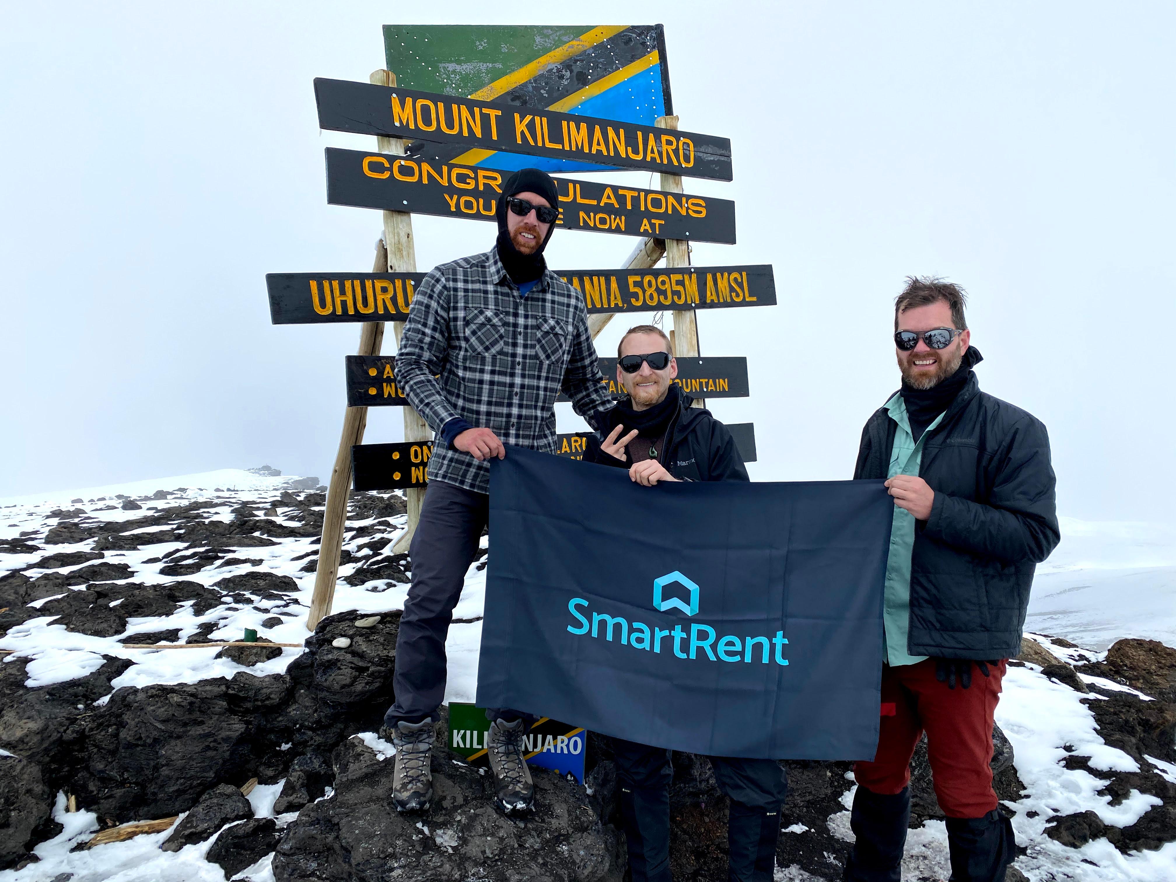 SmartRent trekkers holding up SmartRent flag at peak of Kilimanjaro