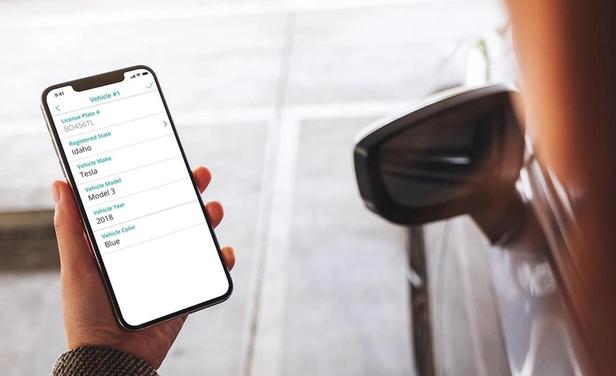 SmartRent user holds a smartphone with parking information displayed on the screen.