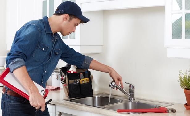 A maintenance technician repairs sink in a multifamily apartment home.