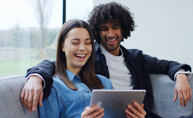 Couple sitting on couch looking at iPad
