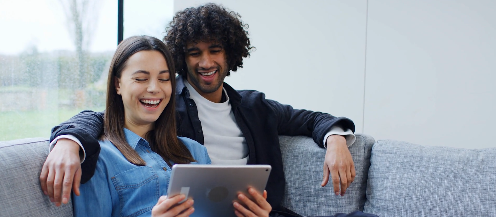 Couple sitting on couch looking at iPad